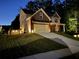 Exterior view of this home showcasing a manicured lawn, brick facade, and a two-car garage at dusk at 5637 Valley Loop, Fairburn, GA 30213