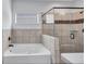 Spa-like bathroom showcases a soaking tub, walk-in shower with bench, and tiled surround for a luxurious experience at 385 Hinton Chase Pkwy, Covington, GA 30016