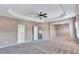 Large bedroom with tray ceilings, fan, and doorway views of a bathroom and hallway for convenience and comfort at 385 Hinton Chase Pkwy, Covington, GA 30016