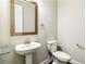 Modern half-bathroom with a pedestal sink, toilet, and minimalist decor at 510 Suwanee Pass Ln, Suwanee, GA 30024