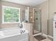 Bathroom featuring a shower with glass door and large soaking tub with stone accents at 4545 Evandale Way, Cumming, GA 30040