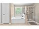 Bathroom featuring a shower with glass door and large soaking tub near a large window at 4545 Evandale Way, Cumming, GA 30040