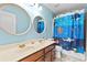 Bright blue bathroom with double vanity, round mirrors, and a playful ocean-themed shower curtain at 4545 Evandale Way, Cumming, GA 30040