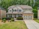 Charming two-story home featuring a stone-accented garage and well-manicured front yard at 4545 Evandale Way, Cumming, GA 30040