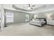 Spacious bedroom with tray ceilings, a ceiling fan, and neutral carpet and decor at 4545 Evandale Way, Cumming, GA 30040