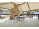 Covered outdoor patio features a stone fireplace, dining table with chairs, and overhead lighting at 4545 Evandale Way, Cumming, GA 30040