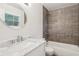 Bathroom featuring a tub shower with gray tiling and a round mirror above a marble-look vanity sink at 875 Waterbrook Ct, Roswell, GA 30076