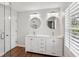 Bright bathroom features double vanity, dual sinks, and round mirrors complemented by modern lighting and wood-look floors at 875 Waterbrook Ct, Roswell, GA 30076