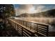 Picturesque view of a wooden pier extending into a tranquil lake with morning fog and a treelined shoreline at 875 Waterbrook Ct, Roswell, GA 30076