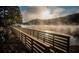Scenic lake view with a wooden bridge and hazy hills in the background, perfect for relaxation at 875 Waterbrook Ct, Roswell, GA 30076