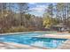 Community swimming pool with clear blue water, surrounded by trees and a nearby pool house at 875 Waterbrook Ct, Roswell, GA 30076