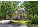 Brick home with an attached garage surrounded by trees, green grass, and lush landscaping at 486 Milledge Gate Se Ter, Marietta, GA 30067
