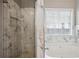 Spa-like bathroom with glass door shower, soaking tub and marble-style accent tiles at 5525 Mayfair Crossing Dr, Lithonia, GA 30038
