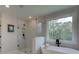 Bright bathroom featuring a soaking tub under a window and frameless glass shower with marble-look tile at 110 Prescott Manor Dr, Canton, GA 30115