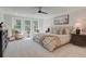 Serene main bedroom featuring a tufted headboard, neutral tones, ample natural light, and a cozy seating area at 110 Prescott Manor Dr, Canton, GA 30115