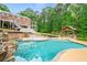 Inviting backyard pool with an outdoor kitchen, hot tub, fire pit, and a multi-story deck overlooking lush green trees at 1212 Lee Whatley Dr, Lithonia, GA 30058