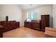 Well-lit bedroom features gleaming hardwood floors, bright window and several wooden dressers at 2108 Waters Edge Trl, Roswell, GA 30075
