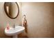 Cozy powder room with pedestal sink, decorative mirror, and warm neutral tones at 2108 Waters Edge Trl, Roswell, GA 30075