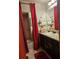 Bathroom with long mirror, dark cabinets, granite countertop, red curtain, and decor at 7848 Rock Rose Ln, Fairburn, GA 30213