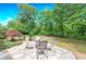 Outdoor dining area includes a stone patio, chairs, and mature landscaping at 9175 Etching Overlook, Johns Creek, GA 30097