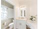 Light-filled bathroom with vanity, white cabinetry, decorative window, and adjacent toilet room with stylish wallpaper at 9175 Etching Overlook, Johns Creek, GA 30097