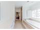 Bright bathroom with a soaking tub, tiled floors, and a glimpse into an adjacent bedroom at 9175 Etching Overlook, Johns Creek, GA 30097