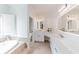 Bright bathroom showcasing soaking tub, tiled floors, and spacious vanity with illuminated mirrors and white cabinetry at 9175 Etching Overlook, Johns Creek, GA 30097