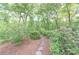 A stone pathway meanders through lush greenery, creating a serene and private garden setting at 9175 Etching Overlook, Johns Creek, GA 30097