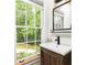Charming bathroom featuring a wood vanity, a sink, natural lighting, and a view to the green outdoor at 3380 Hill Forest Nw Trl, Acworth, GA 30101