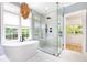 Bright bathroom featuring a freestanding tub, glass shower, and natural light from large window at 3380 Hill Forest Nw Trl, Acworth, GA 30101