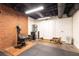 Basement workout area with a rowing machine, gym flooring, and brick accent wall at 3380 Hill Forest Nw Trl, Acworth, GA 30101