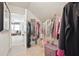 Walk-in closet with a variety of clothes; bedroom with window view in background at 8145 Stone Hill Rd, Cumming, GA 30028