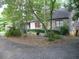 Charming stone house with red-trimmed windows is nestled in a serene, wooded landscape at 8145 Stone Hill Rd, Cumming, GA 30028
