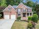 Elegant two-story brick home with a manicured lawn, flower beds, and a two-car garage at 1273 Promontory Ln, Marietta, GA 30062