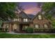 Beautiful two-story brick home with a well-manicured front yard, a covered porch, and beautiful landscaping at sunset at 448 Cape Ivey Dr, Dacula, GA 30019