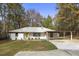 Charming single-story home features a yellow door and attached carport, nestled among mature trees at 2013 Ridge Rd, Dallas, GA 30157