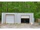Metal storage building with two garage doors and a concrete pad in front surrounded by a lush green forest at 3785 Willow Ridge Rd, Douglasville, GA 30135