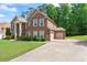 A spacious, two-story brick home with attached garage and a wide driveway, surrounded by lush greenery at 305 Spooner Dr, Mcdonough, GA 30252