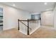 The carpeted hallway has wooden railings, neutral walls and offers views into the living room and a bedroom at 340 Paulownia Cir, Mcdonough, GA 30253
