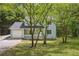 Two-story home with light green siding, white trim, and an attached garage nestled among mature trees at 3688 Burnley Court, Lithonia, GA 30038