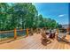 Outdoor deck featuring wood furnishings, a fire pit, and expansive views of surrounding lush trees at 5925 Boulder Bluff Dr, Cumming, GA 30040