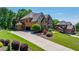 Spacious driveway leading to a brick home with lush landscaping and an attached garage at 5925 Boulder Bluff Dr, Cumming, GA 30040