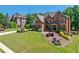 Elegant brick home featuring a manicured front lawn, mature trees, and a welcoming entrance at 5925 Boulder Bluff Dr, Cumming, GA 30040