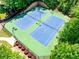 Overhead shot of blue and green tennis courts, fenced in and surrounded by trimmed shrubbery at 5925 Boulder Bluff Dr, Cumming, GA 30040
