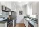 Galley kitchen featuring stainless steel appliances, white cabinets, and unique backsplash at 318 Glenwood Se Ave, Atlanta, GA 30312