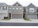 Townhome exterior showcasing the building's facade, garages, and well-maintained landscaping at 7621 Avalon Blvd, Fairburn, GA 30213