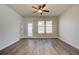 Bright living room featuring a ceiling fan, wood floors, and large windows overlooking the backyard at 288 Abbotts Crossing Cir, Conyers, GA 30094