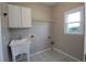 Functional laundry room features a utility sink, overhead cabinet, and a window for natural light at 5029 Preservation Pointe, Kennesaw, GA 30152