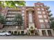 Beautiful brick apartment building with balconies, arched entryway, and lush green trees at 77 Peachtree Ne Pl # 608, Atlanta, GA 30309