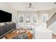 Sunlit living space with a white sofa, modern TV console, unique coffee table and staircase to the second floor at 1371 Walking Way, Atlanta, GA 30316